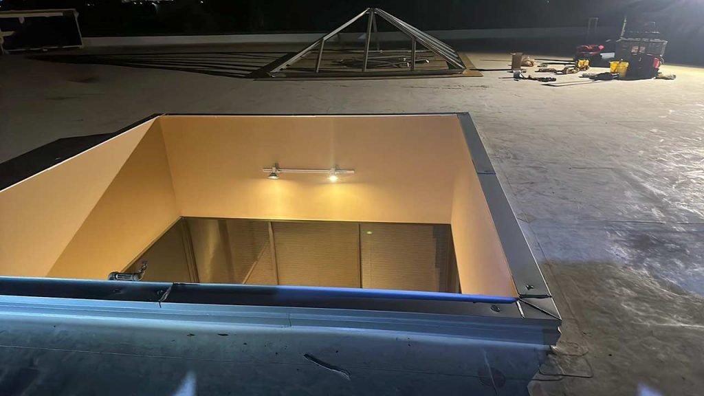 An image of a skylight frame and curb and roof opening ready for it taken at night.