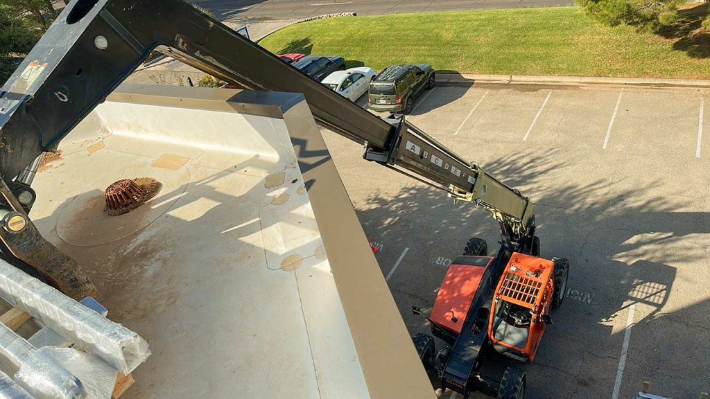 An image of a forklift hoisting a pallet of frame parts to the roof.