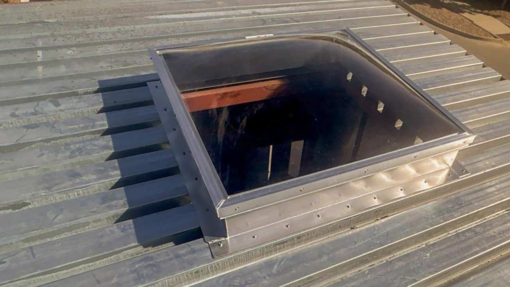 Bronze acrylic skylight land aluminum curb on a metal roof.