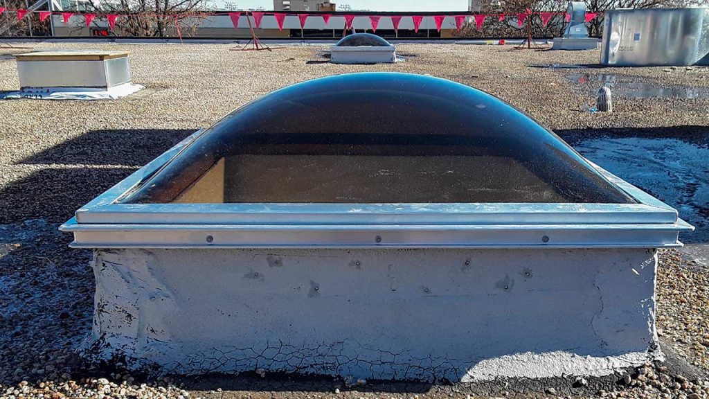 An acrylic dome skylight mounted on an aluminum curb on the roof.