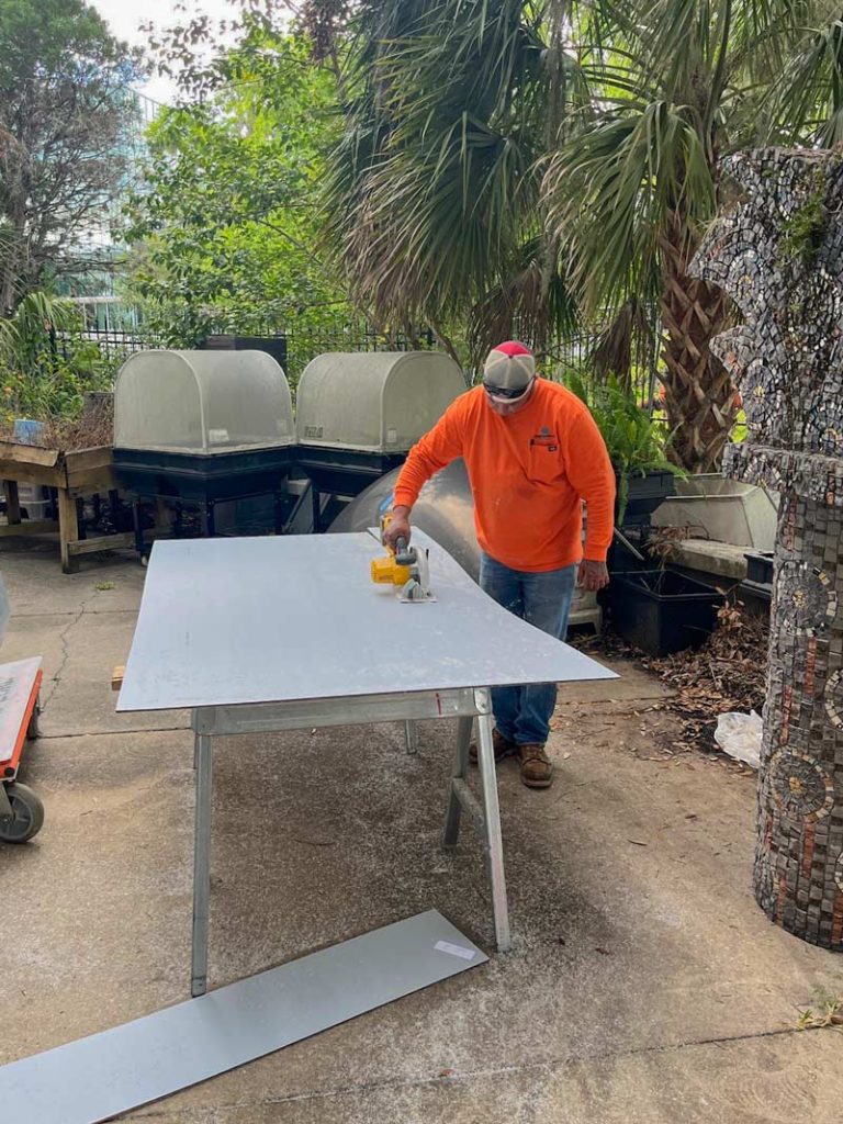 A man is cutting a polycarbonate panel while working in a yard.