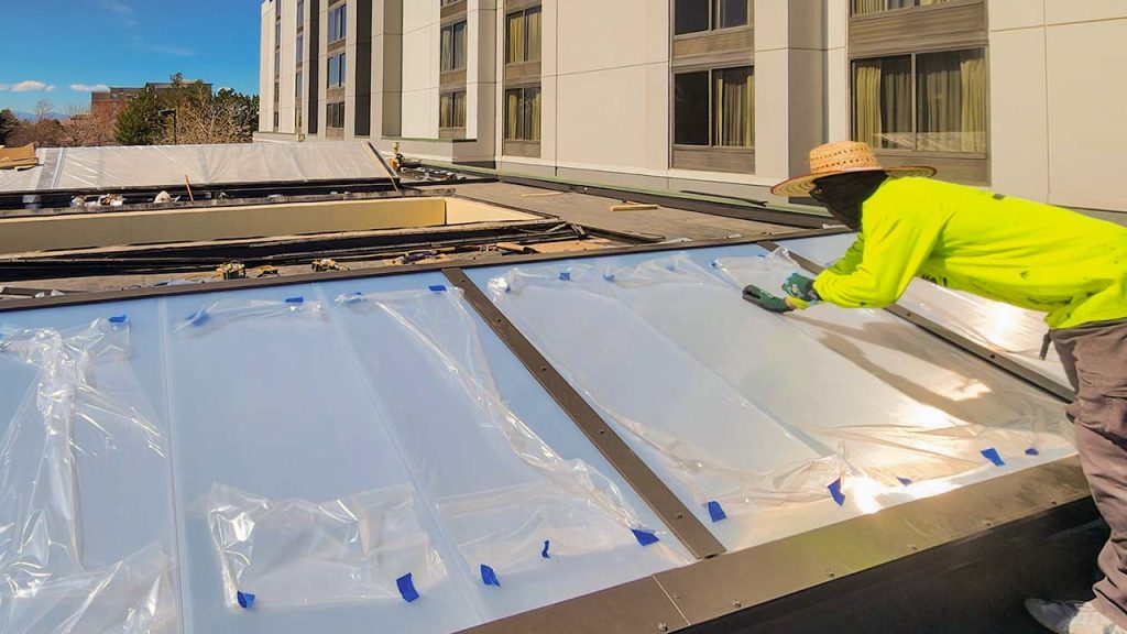 A technician is remnoving the protective film on the installed skylight panels.