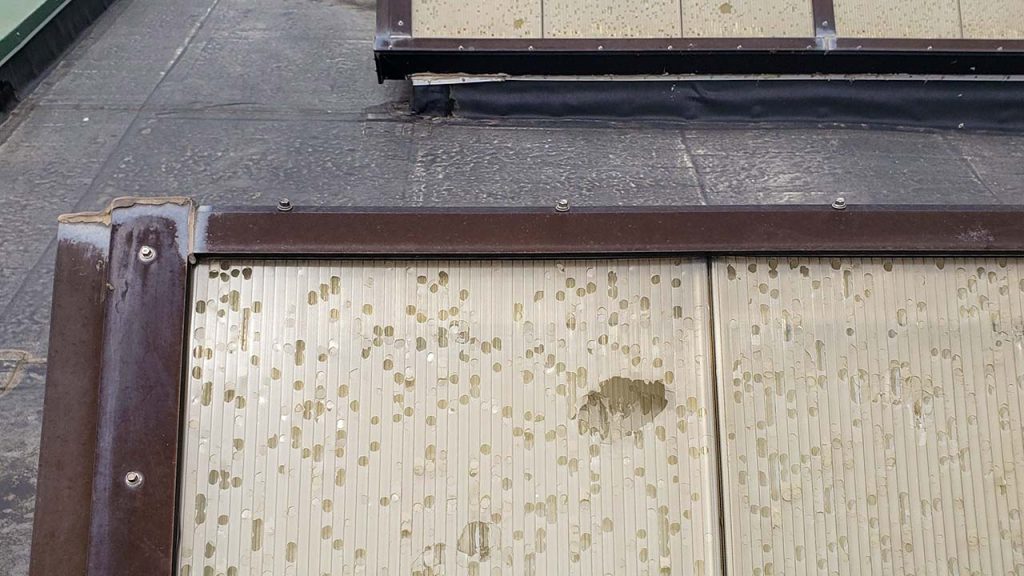 The yellowed acrylic skylight panels have been severely damaged form hail.