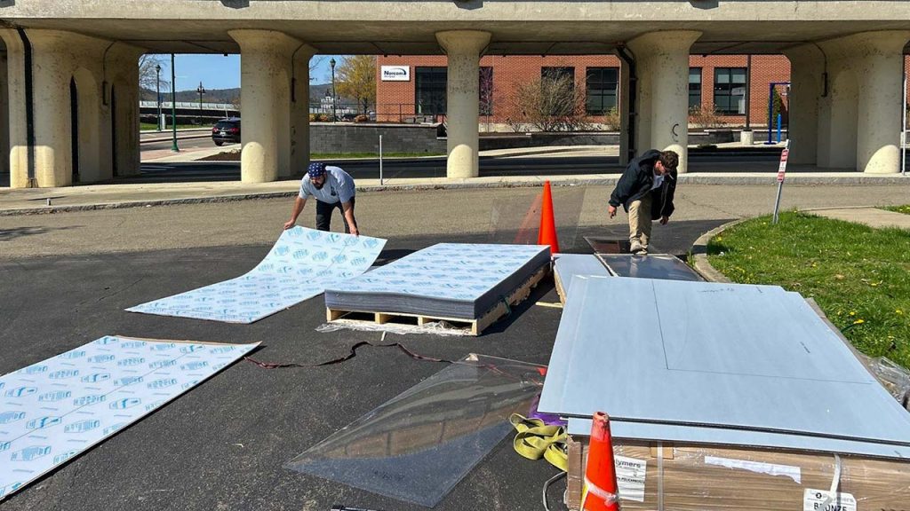 Technicians are unstacking polycarbonate sheets preparing to cut them to size.