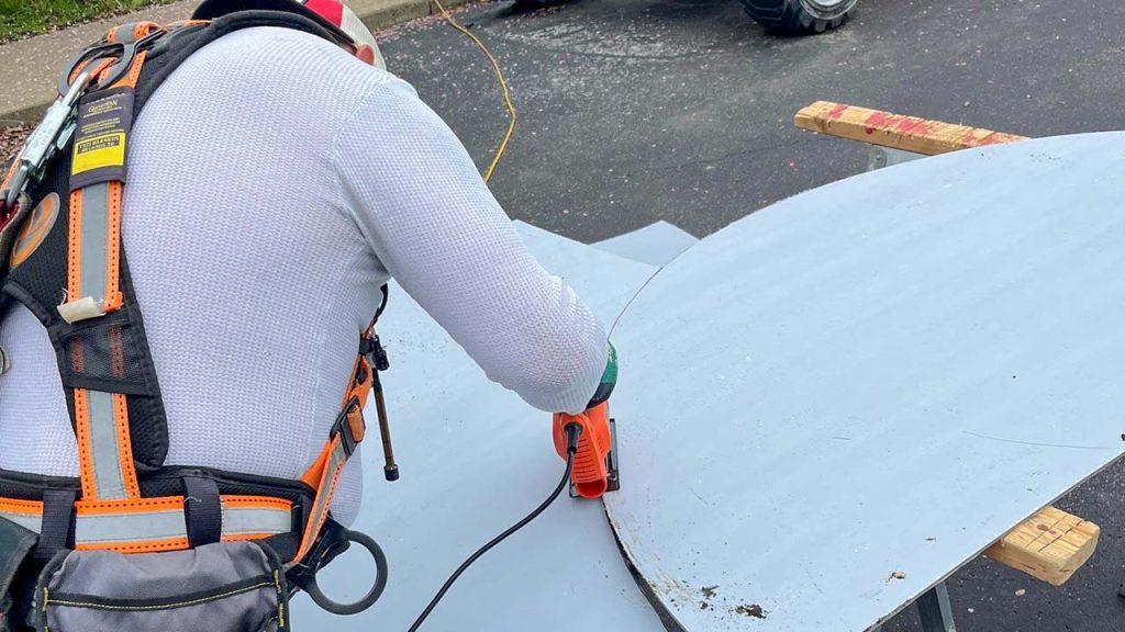 Technician is cutting a polycarbonate sheet to fit an end panel of the barrel vault skylight.