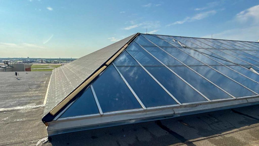 Glass ridge skylight with covered end wall on commercial roof