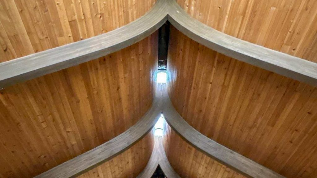 Interior view of church wood plank ceiling with curved glulam arches surrounding narrow linear skylight openings