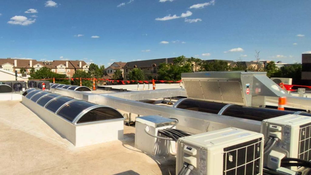 Large commercial barrel vault skylights installed alongside HVAC units on a flat rooftop.