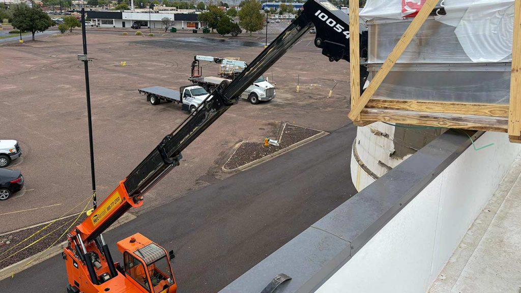Crane lifting a packaged VELUX unit skylight onto the roof of a VASA Fitness facility